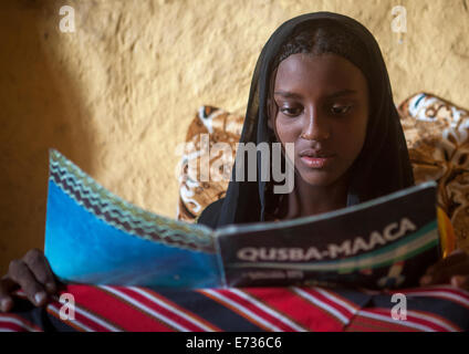 Mahammed Fatouma dall etnia afar la lettura di un libro di scuola, Afambo, Etiopia Foto Stock