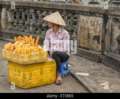 Giovane donna vendita di pane fresco in strada. Foto Stock