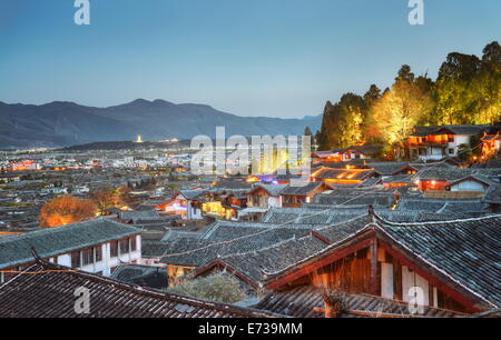 I tetti di Lijiang Dayan, sito UNESCO, con alberi illuminati di Lion Hill, Yunnan, Cina Foto Stock