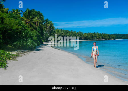 Donna che cammina su una spiaggia di sabbia bianca, Il Nanuya Lailai island, la Blue Lagoon, Yasawas, Figi, South Pacific Pacific Foto Stock