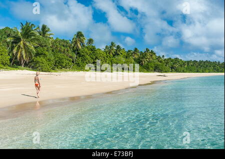 Donna che cammina su un orlata di palme spiaggia di sabbia bianca di Haapai, Haapai, Isole Tonga, South Pacific Pacific Foto Stock