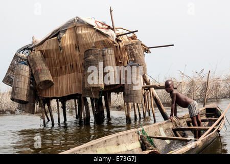 Africa, Benin, Ganvie. Giovane ragazzo in piroga da stilted struttura con trappole di pesce. Foto Stock