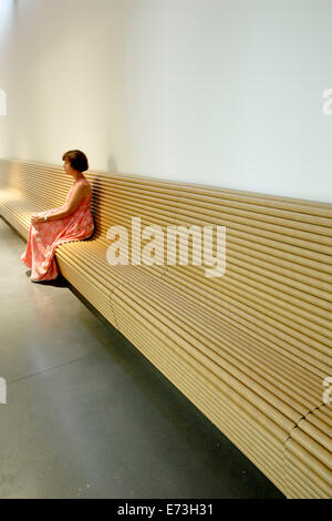 Donna seduta su un banco di lavoro realizzato in tubi di cartone, Aspen Art Museum (dall'Architetto Shigeru Ban), Aspen Colorado, STATI UNITI D'AMERICA Foto Stock