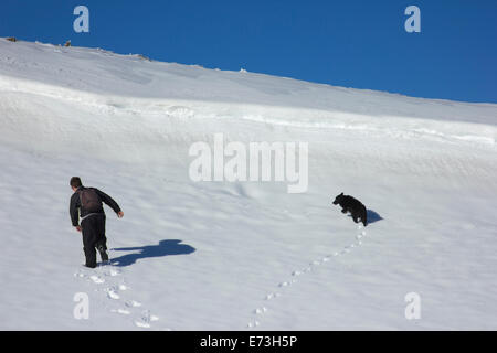 Escursionista e cane formando un cuore nella neve Foto Stock