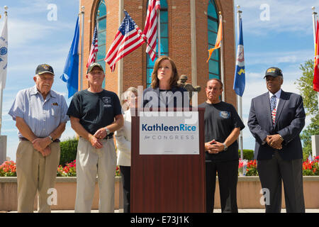 Prato est, New York, Stati Uniti d'America. Il 3 settembre, 2014. KATHLEEN riso, a podio, democratico congressuale del candidato (NY-04), rilascia un white paper sulla politica dei veterani e annuncia la formazione della sua campagna di veterani del Comitato consultivo, a Veterans Memorial a Eisenhower Park, dopo touring Northport VA Medical Center con sost. in uscita CAROLYN MCCARTHY (in camicia bianca). Congressista McCarthy e 4 membri del comitato unite riso alla conferenza stampa: PAOLO ZYDOR, (in maglietta blu) di Merrick, U.S. Navy, coreano veterano di guerra; PAT YNGSTROM, (in black T-shirt e tappo) di Merrick, U.S. © Ann e Parry/Ala Foto Stock