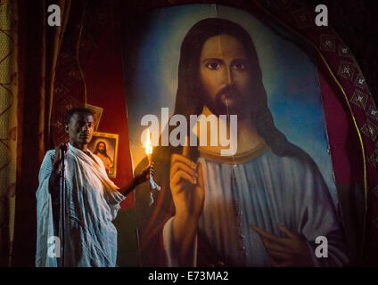 Sacerdote tenendo una candela all'interno di una chiesa rupestre, Lalibela, Etiopia Foto Stock