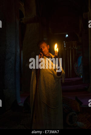 Sacerdote tenendo una candela all'interno di una chiesa rupestre, Lalibela, Etiopia Foto Stock