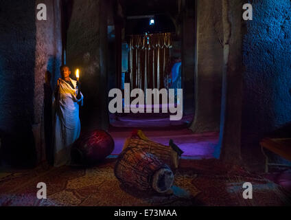 Sacerdote tenendo una candela all'interno di una chiesa rupestre, Lalibela, Etiopia Foto Stock