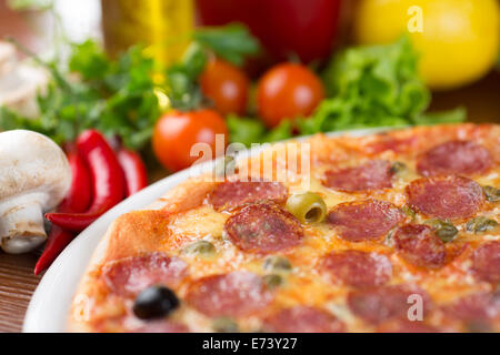 Salame salsicce pizza closeup sulla tavola con verdure Foto Stock