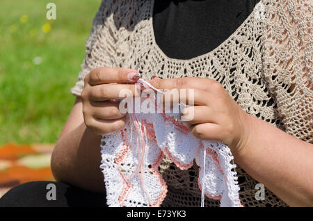 La donna a maglia degli aghi di tessitura rari di tessuti a maglia in filo bianco. Foto Stock