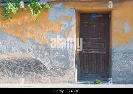 Una parete con sfaldamento giallo lavori in gesso e una porta di legno da Konya, Turchia Foto Stock