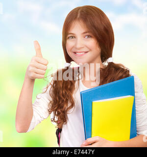 Closeup ritratto di felice carino teen ragazza con i libri di testo e il pollice in su il divertimento all'aperto, mostrando un buon gesto, si torna a scuola Foto Stock