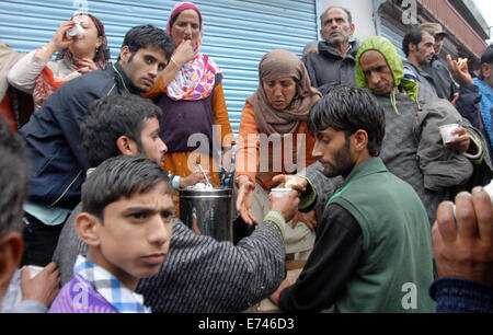 Srinagar, Indiano Kashmir amministrato6th sett, 2014: persone distribuire alimenti articoli fra i bisognosi di persone colpite il pedaggio luogo 100 nelle peggiori inondazioni nello stato in quasi sei decenni. Sette persone sono morte in due diversi incidenti di una casa di collassare a causa di frana provocata dalle forti piogge nel distretto di Udhampur e altri quattro corpi sono stati ritrovati nel distretto di Rajouri, un membro ufficiale del governo detto.(Sofi Suhail/Alamy Live News ) Foto Stock