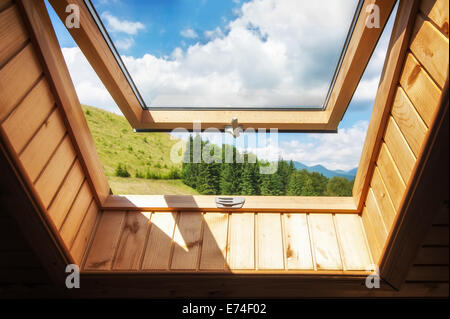 Aprire la finestra presso il village casa in legno in montagna. La magnifica vista del paesaggio estivo con bosco e prato sotto il cielo blu Foto Stock