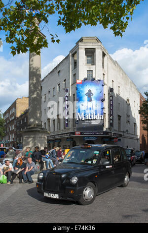 Il Cambridge Theatre di Londra con il pilastro al centro del Seven Dials nodo stradale in primo piano. Foto Stock