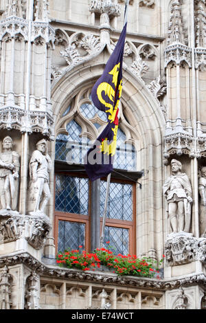 La facciata della impressionante del secolo XV Municipio gotico di Leuven (Lovanio), Belgio, con il "Leone fiammingo' bandiera delle Fiandre. Foto Stock