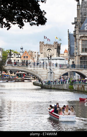 Turisti che si godono un viaggio in barca sul canale nella città di Gand in Belgio, con il Castello di Gravensteen in background. Foto Stock