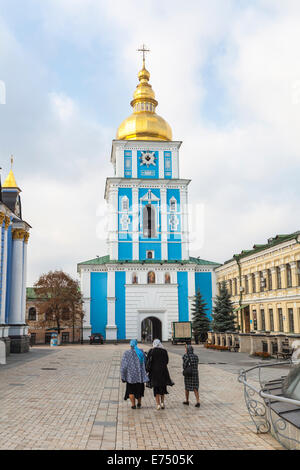 Tre donne locali camminano verso l'ingresso principale dell'iconico edificio storico, il monumento blu del monastero della cupola dorata di San Michele, Kiev, Ucraina Foto Stock