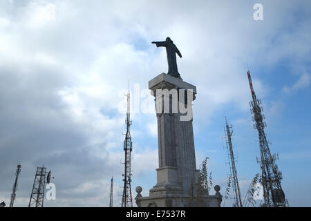 Statua di Cristo su un alto basamento in cima Monte Toro, Minorca, Spagna. Le antenne TV e telefono cellulare circondano la figura, che ha le braccia aperte Foto Stock