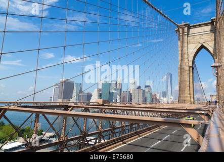 Sullo skyline di New York dal ponte di Brooklyn con un tipico taxi giallo sul ponte Foto Stock