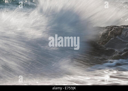 Onde che si infrangono sulle rocce Foto Stock