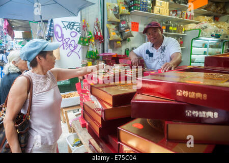 New York, Stati Uniti d'America. Il 7 settembre, 2014. La shopper in Chinatown in New York acquista una scatola di mooncakes domenica 7 settembre, 2014 per Mid-Autumn Festival che si svolge il 8 settembre. La deliziosa e tradizionale prodotto cotto è mangiato durante il Mid-Autumn Festival e sono popolari come doni. Il perfettamente rotonda pasticceria può essere dolce o salato, riempito con semi di loto o salati Duck egg. Le torte rappresentano la luna piena sull'ottavo mese, il quindicesimo giorno in cinese (lunare) Calendario. Credito: Richard Levine/Alamy Live News Foto Stock