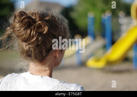 Schoolyard parco giochi - profilo della madre guarda al parco giochi Foto Stock