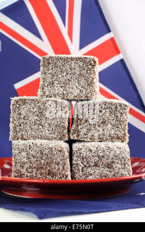 Australian tradizionale torta, con torta Lamingtons, su red polka dot piastra con bandiera australiana contro uno sfondo bianco. Foto Stock