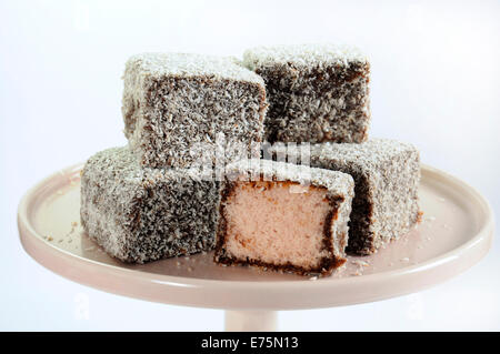 Australian tradizionale torta, Lamington, il rosa pallido cake stand contro uno sfondo bianco. Primo piano. Foto Stock