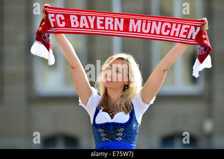 Giovane donna che indossa un vestito con grembiule, sostenitore del FC Bayern, tenendo in mano un ventilatore sciarpa, Germania Foto Stock