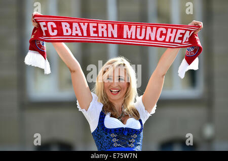 Giovane donna che indossa un vestito con grembiule, sostenitore del FC Bayern, tenendo in mano un ventilatore sciarpa, Germania Foto Stock