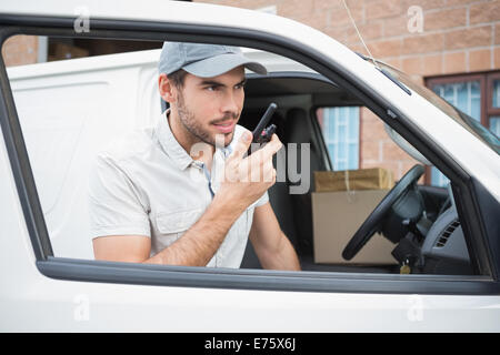 Driver di consegna a parlare su walkie talkie dal suo furgone Foto Stock
