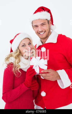 Attraente coppia giovane indossando cappelli di Babbo Natale con il dono Foto Stock