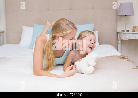 Carino bambina e madre sul letto Foto Stock