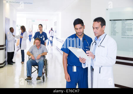 Medico e infermiere lettura grafico medico in ospedale in corridoio Foto Stock