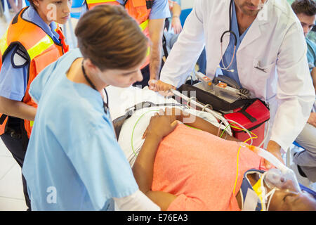 Medico, infermiere e personale paramedico esaminando il paziente sulla barella Foto Stock
