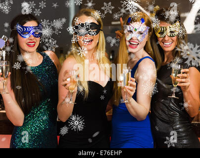 Immagine composita di ridere amici indossando maschere azienda bicchieri da champagne Foto Stock