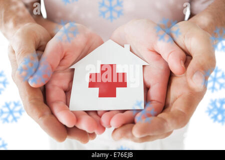 Immagine composita della giovane azienda casa di carta con la croce rossa in mani Foto Stock