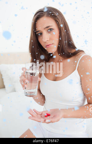 Immagine composita della donna che guarda preoccupato come lei sta per prendere due pillole con acqua, Foto Stock