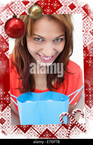 Immagine composita di adolescente sorridendo dopo guardando il suo sacchetto di acquisto Foto Stock