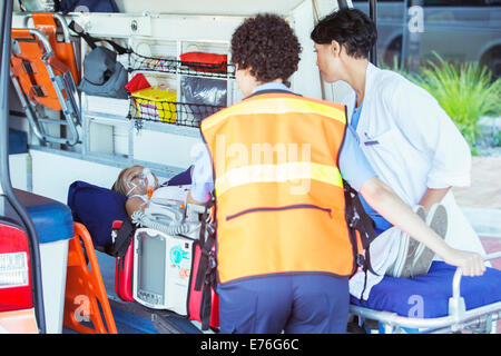 I paramedici wheeling paziente fuori ambulanza Foto Stock