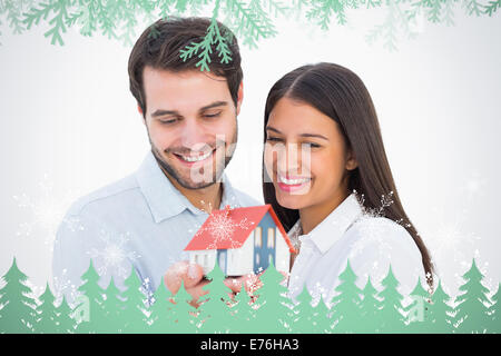 Immagine composita di attraente coppia giovane tenendo un modello di casa Foto Stock