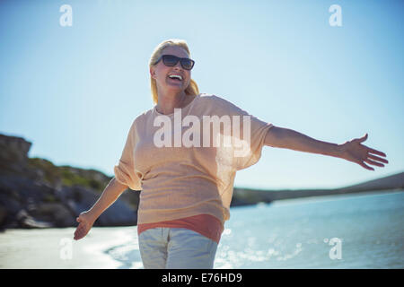 I vecchi donna sorridente nel sole sulla spiaggia Foto Stock