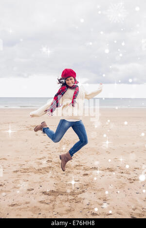 Immagine composita della donna in eleganti abiti caldi saltando al beach Foto Stock