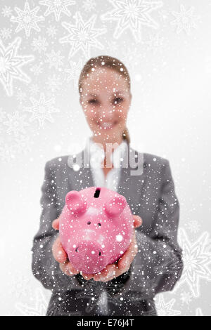 Immagine composita di salvadanaio essendo tenuto dalla sorridente dipendente della banca Foto Stock