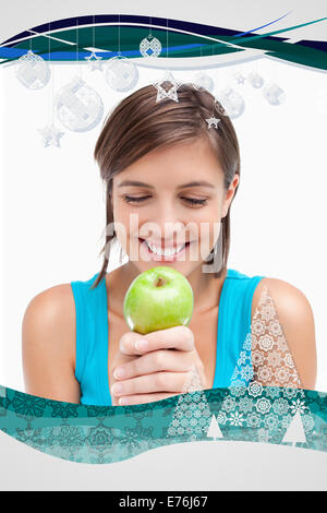 Immagine composita di sorridere adolescente guardando una mela verde posto sulle sue mani incrociate Foto Stock