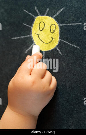 Macro close up del neonato del disegno a mano un sorriso giallo sole sulla lavagna. Foto Stock