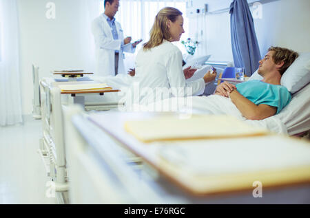 Medico di parlare al paziente nel letto di ospedale Foto Stock