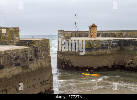 Un canoeist paddling fuori del porto di Charlestown, un villaggio ed un porto sulla costa meridionale della Cornovaglia, England Regno Unito Foto Stock