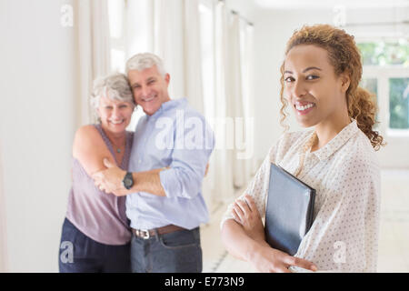 Coppia di anziani abbracciando con donna sorridente Foto Stock